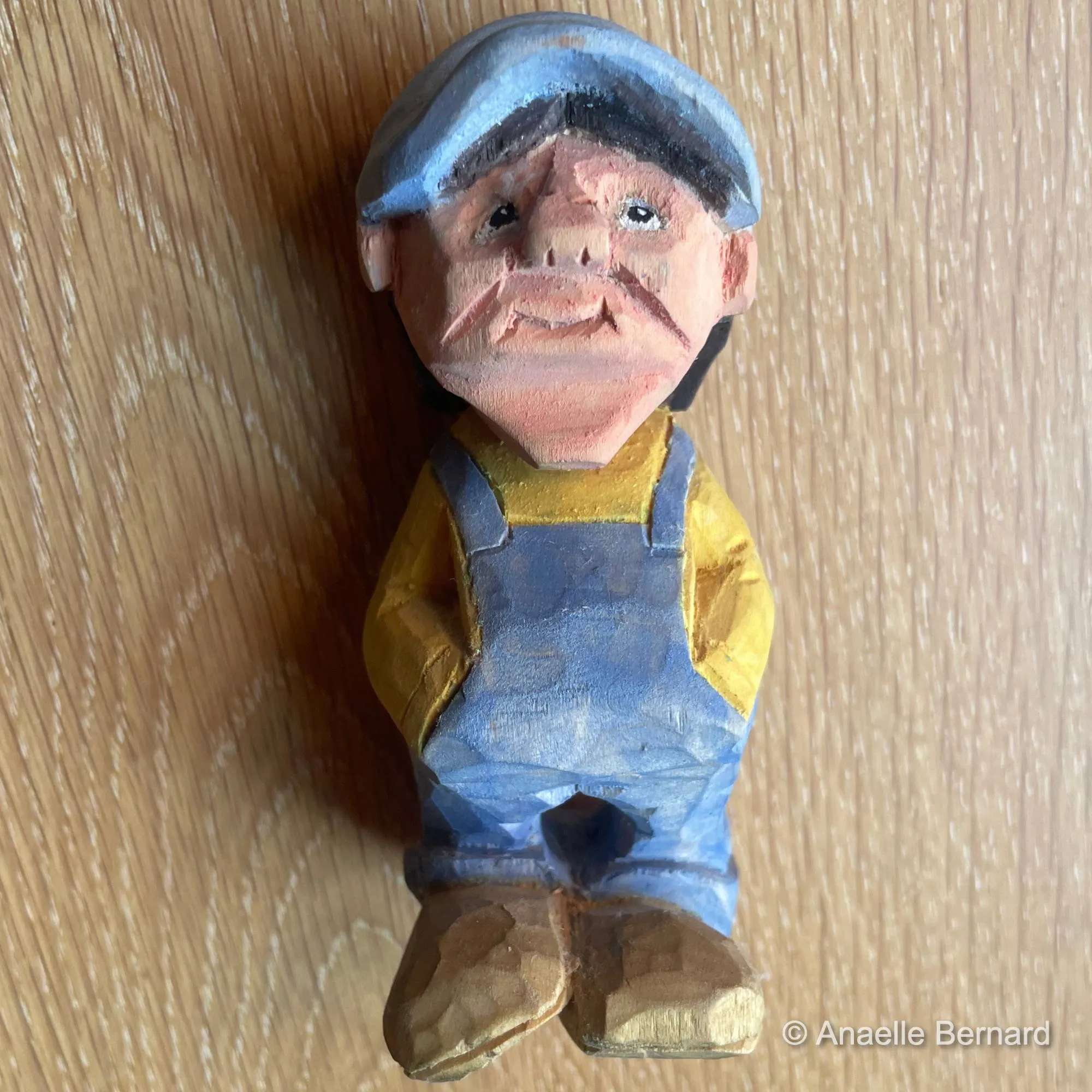 Entre innocence et sagesse, cette œuvre capture l'essence d'un instant suspendu, où la casquette devient le symbole d'une jeunesse éternelle. Les couleurs vives de l'acrylique dansent sur le bois, évoquant la joie simple des jours sans souci.